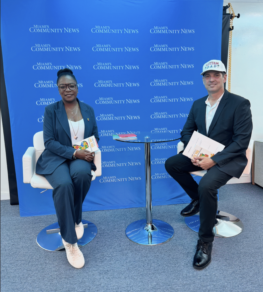 Smiling co-founder of South Florida Autism Charter School sitting with Miami Autism Dad Victor Antunez.